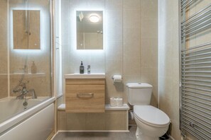 Ein Badezimmer mit Badewanne, Toilette und Waschtisch.