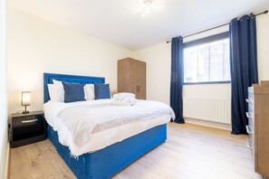 Un dormitori amb un llit, una vetust, un armari i una finestra amb cortines.