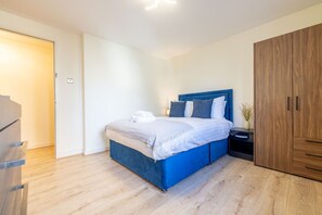 Ein Schlafzimmer mit Bett, Nachttisch, Kleiderschrank und einer Tür.