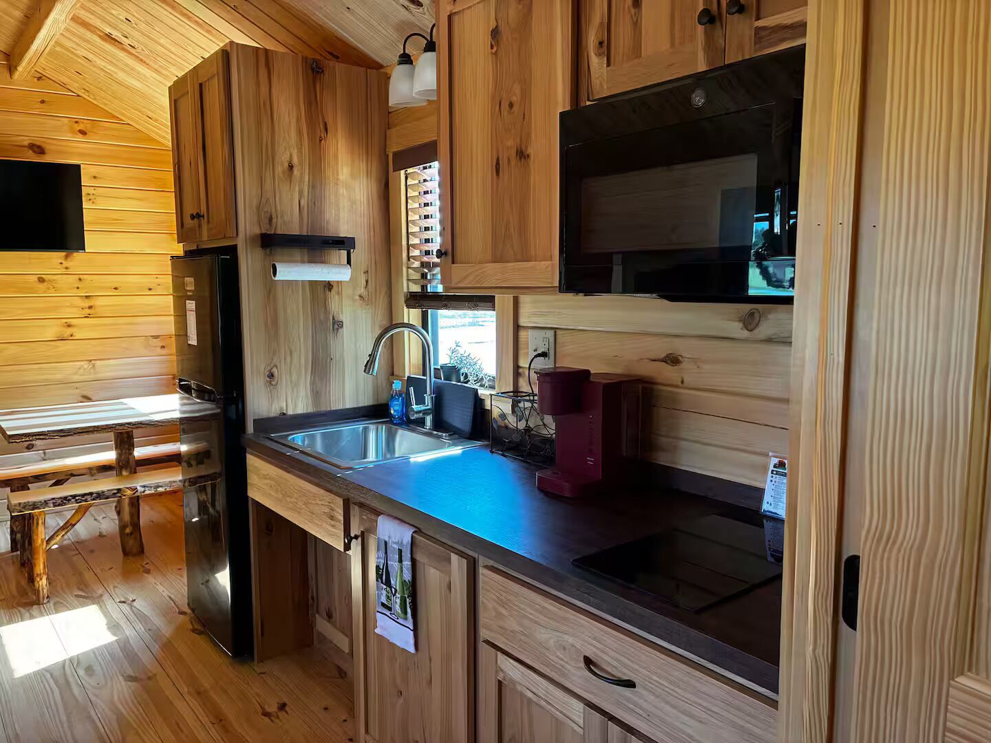 A compact kitchen with wooden cabinetry, a stainless steel sink, and a built-in microwave.