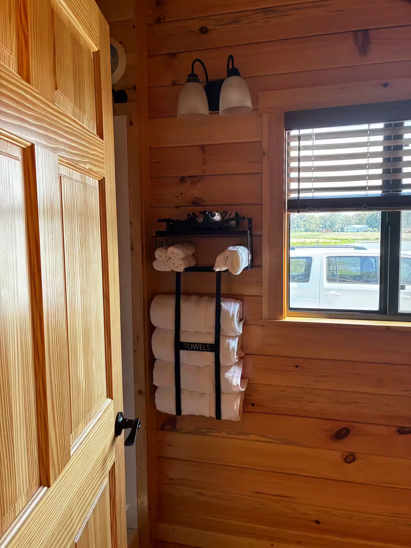A wooden interior with a towel rack and a window with blinds.
