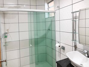 Un bagno con box doccia in vetro, lavandino bianco e specchio.