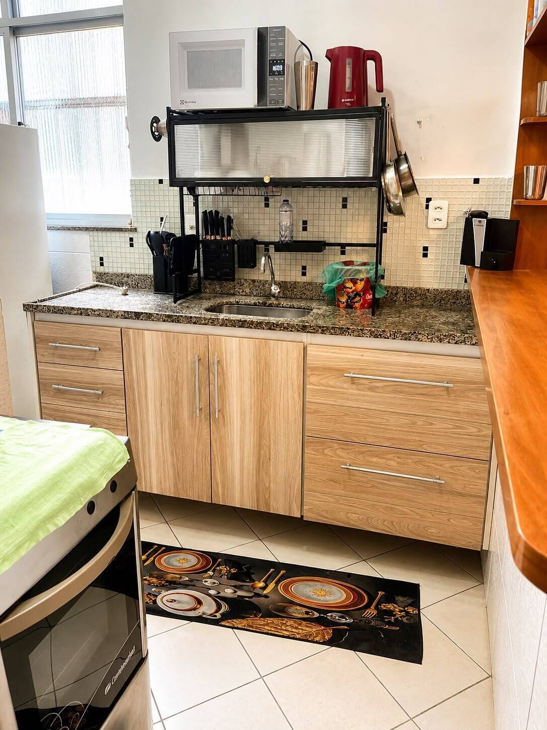 Una cocina compacta con microondas, cafetera y un lavamanos pequeño.