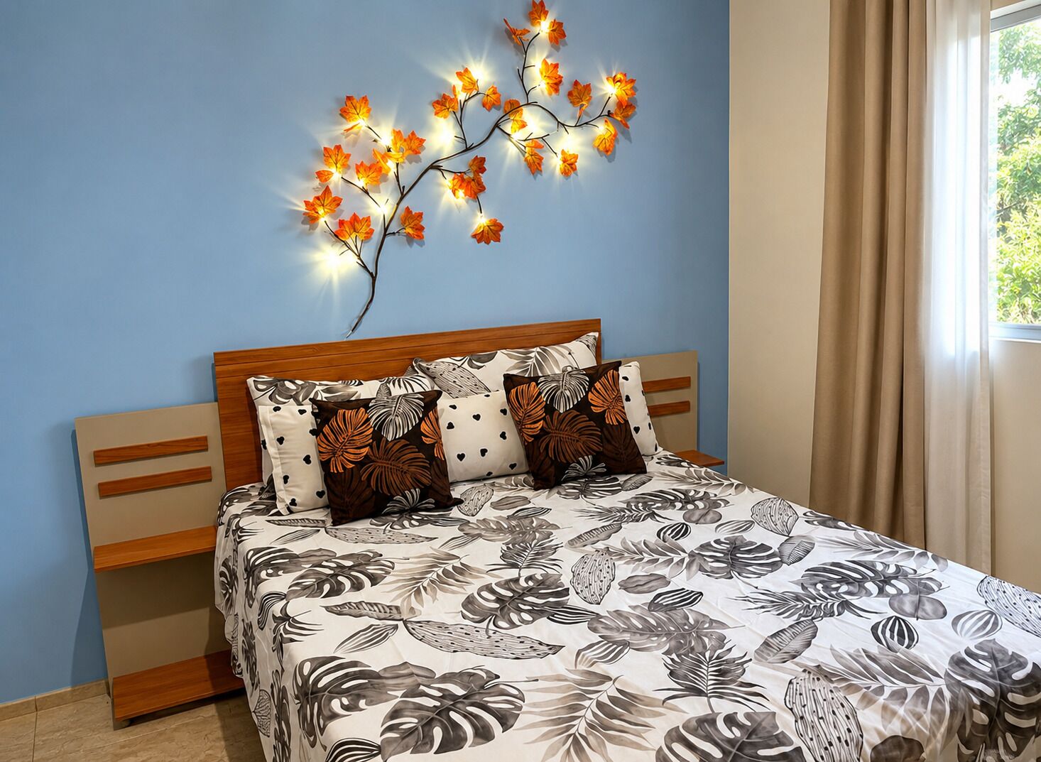 Une chambre à coucher comprenant un lit, une table de chevet, un luminaire fixé au mur et une fenêtre avec des rideaux.