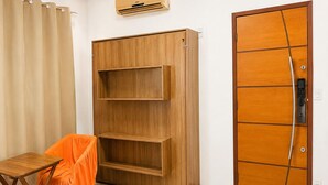 Una habitación con un armario de madera, una mesita con una silla y una puerta con picaporte.