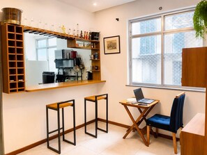 A compact kitchen with a bar area, a dining table with chairs, and a window with a view.