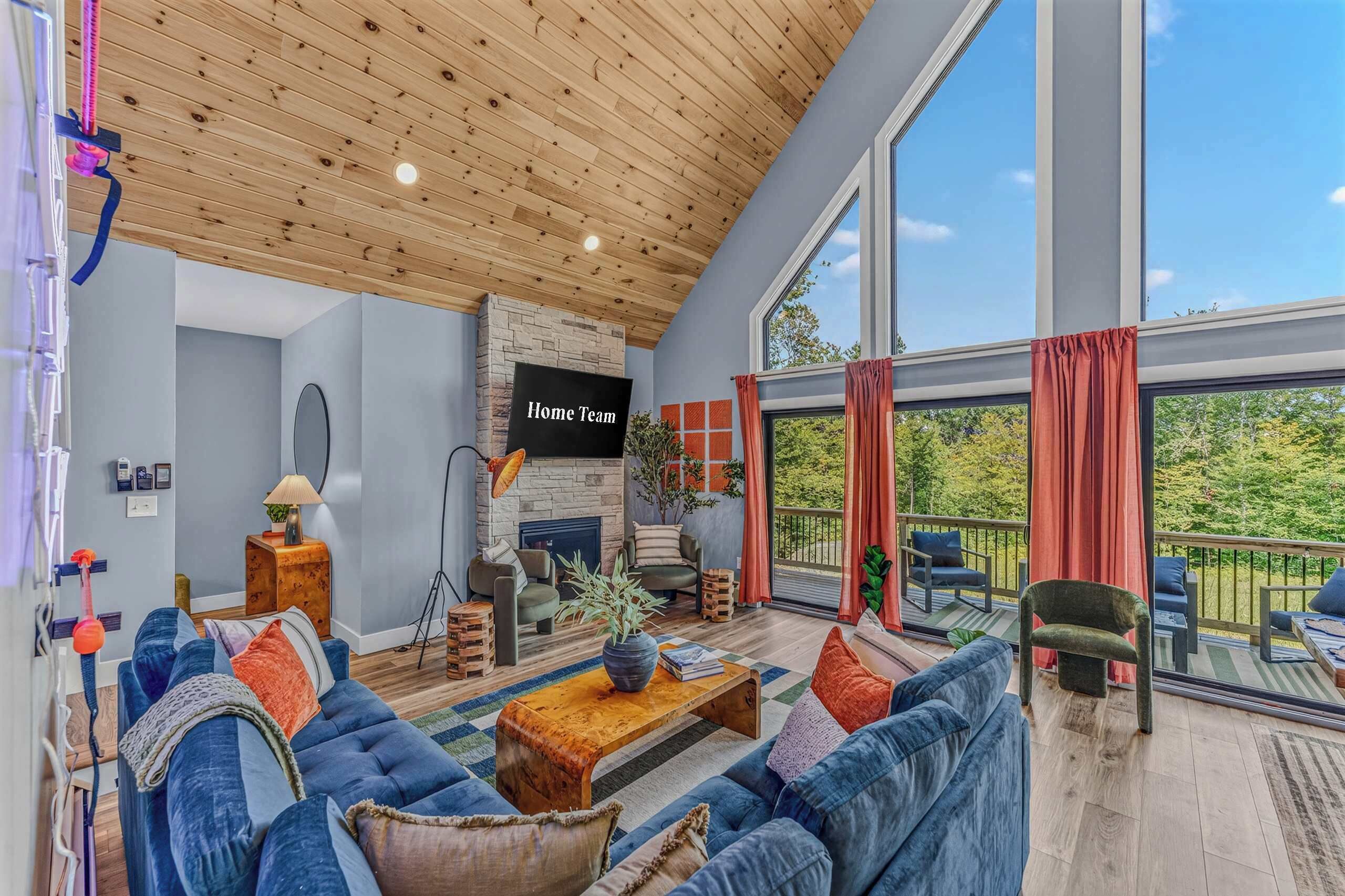 A spacious living room with a large sofa set, a fireplace, and a view of the outdoors through large windows.