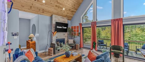 A spacious living room with a large sofa set, a fireplace, and a view of the outdoors through large windows.