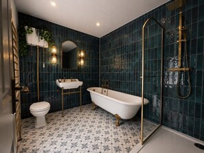 Et badeværelse med et fristående badekar, toilet og håndvask.