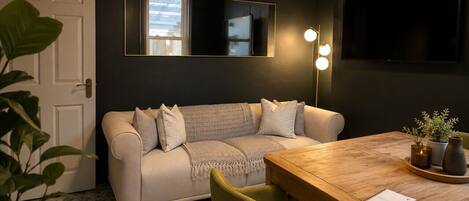 A modern living room with a sofa, a dining table, and a chandelier.