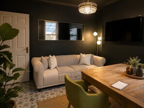 En moderne stue med sofa, spisebord og en lysekrone.