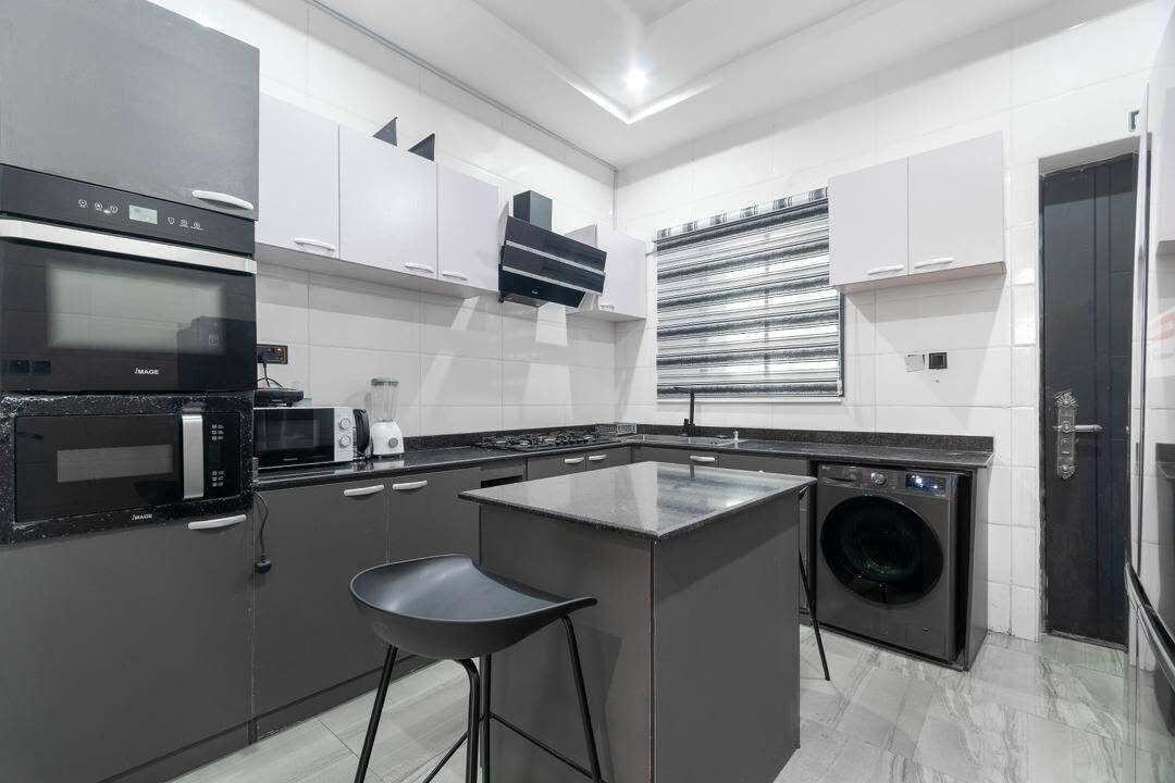 Une cuisine moderne dotée d’un îlot central, d’appareils électroménagers intégrés et d’un lave-linge.