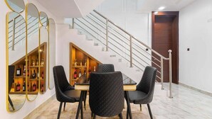 Uma área de refeições com mesa, cadeiras, adega e escada.