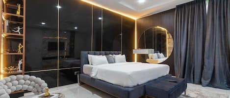 A modern bedroom with a large bed, a built-in wardrobe, and a round mirror.