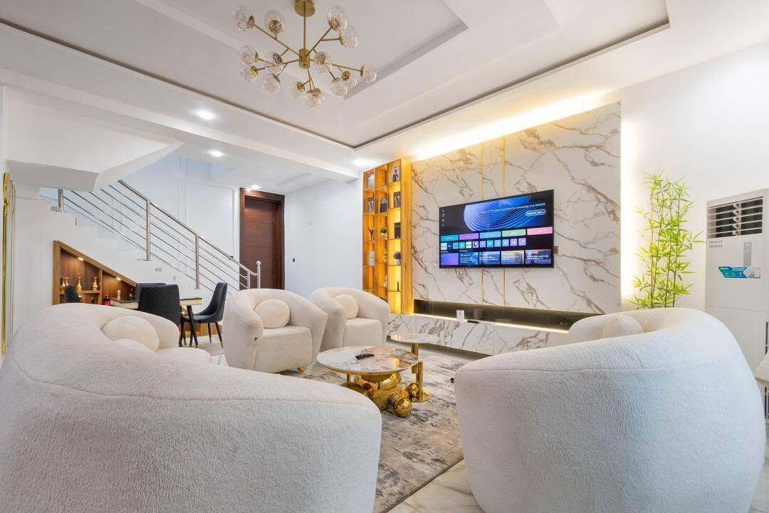 Una sala de estar moderna con un televisor de pantalla plana, asientos cómodos, una escalera y un revestimiento decorativo.