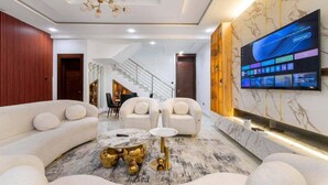 Uma sala de estar moderna com sofá, mesa de centro e televisão fixada na parede.