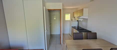 Een kleine keuken met een eethoek, een deur naar een andere kamer en een raam voor natuurlijk licht.