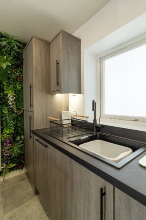 Eine moderne Küche mit Holzschränken, einer schwarzen Arbeitsplatte, einem Spülbecken und einem Fenster.