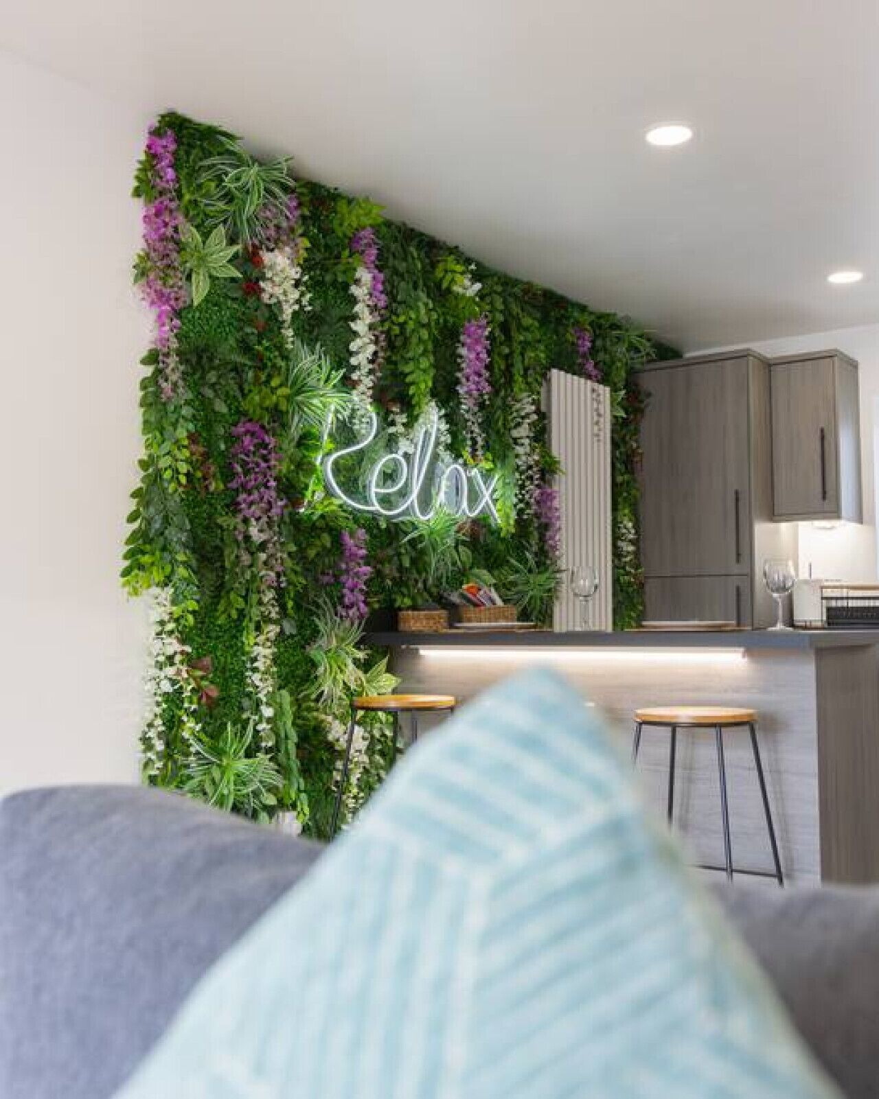 Eine moderne Küche mit einer vertikalen Gartenwand, einer Neonreklame und einer Bar.