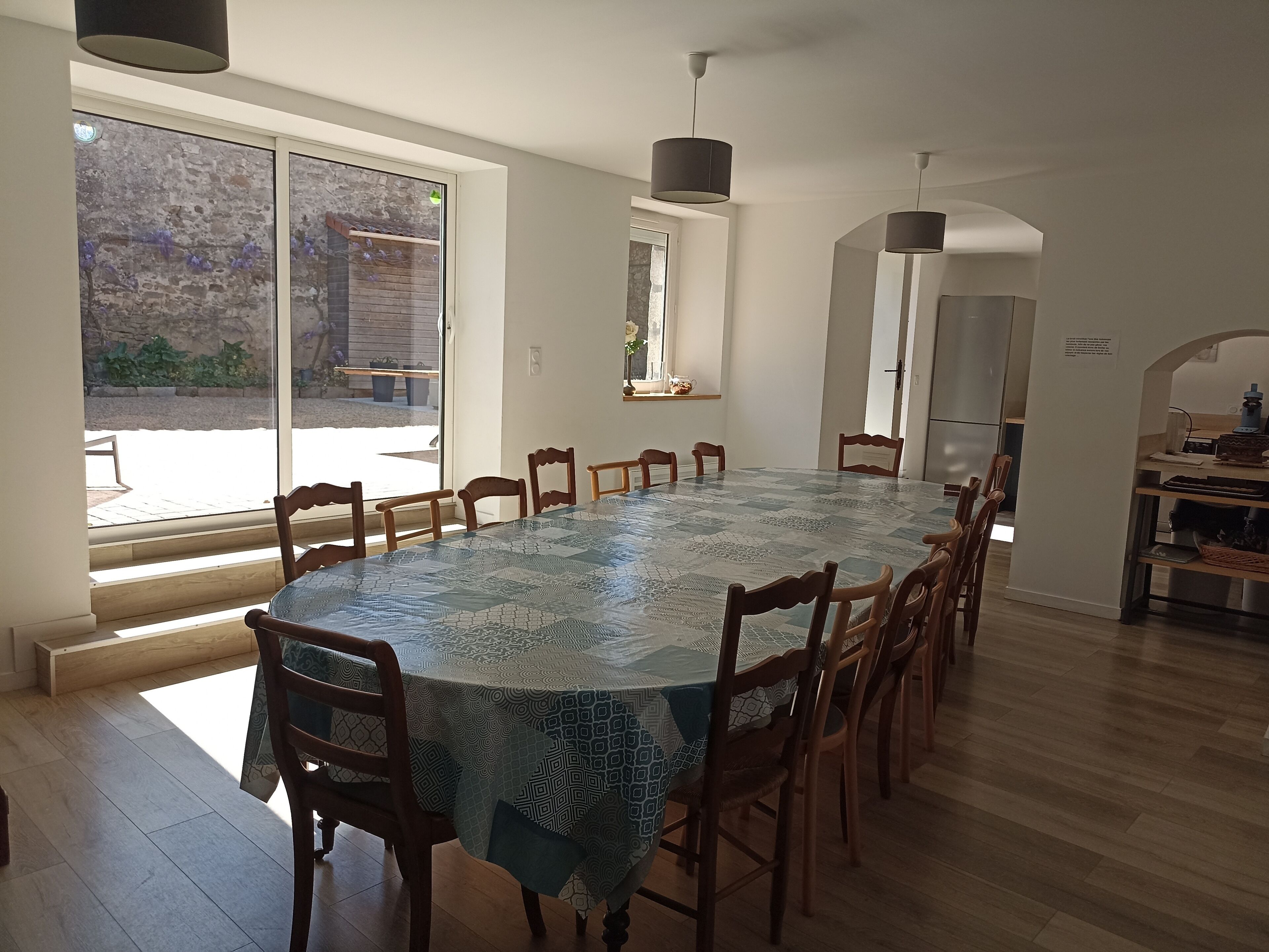 Un comedor con una mesa larga, varias sillas y vistas al exterior a través de un ventanal.