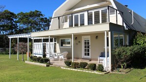 Een tweelaags huis met een overdekte veranda, een voordeur en een kleine tuin.
