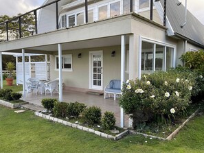 A two-story house with a covered patio area, a dining table with chairs, and a blue sofa. - Capbreton Waterfront Retreat (Clarence Point)