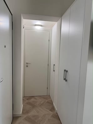 Un pasillo con una puerta cerrada, un armario y una lámpara en el techo.
