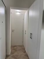 Un pasillo con una puerta cerrada, un armario y una lámpara en el techo.