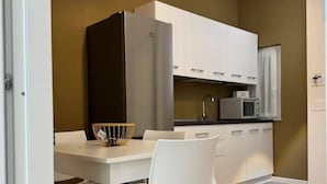 A modern kitchen with white cabinetry, a built-in microwave, and a dining area with a white table and chairs. - HOUSE on SUNDAY (Crotone)