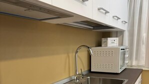 A modern kitchen with a built-in stovetop, a stainless steel sink, and white cabinetry. - HOUSE on SUNDAY (Crotone)