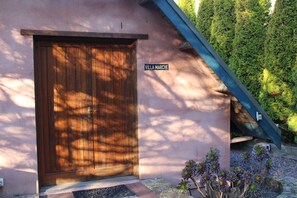 A wooden door with a metal handle, a nameplate reading 'VILLA MARCHE', and a small garden with succulents.