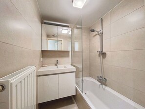 Ein Badezimmer mit einem weißen Waschbecken, Spiegel und Dusche.