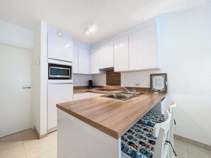 Eine moderne Küche mit weißen Schränken, einer Holz Arbeitsplatte, einem eingebauten Backofen und einer Edelstahl-Spüle.