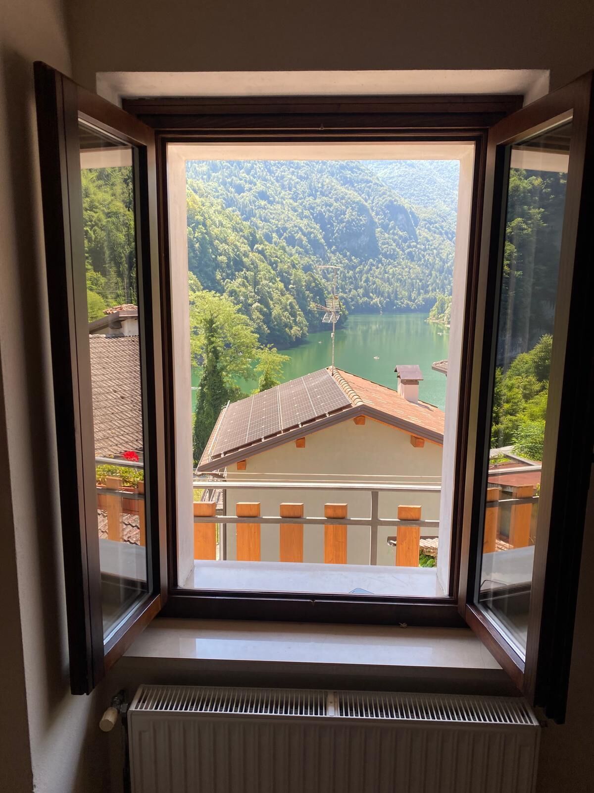 A window with a view of a lake surrounded by forested hills.