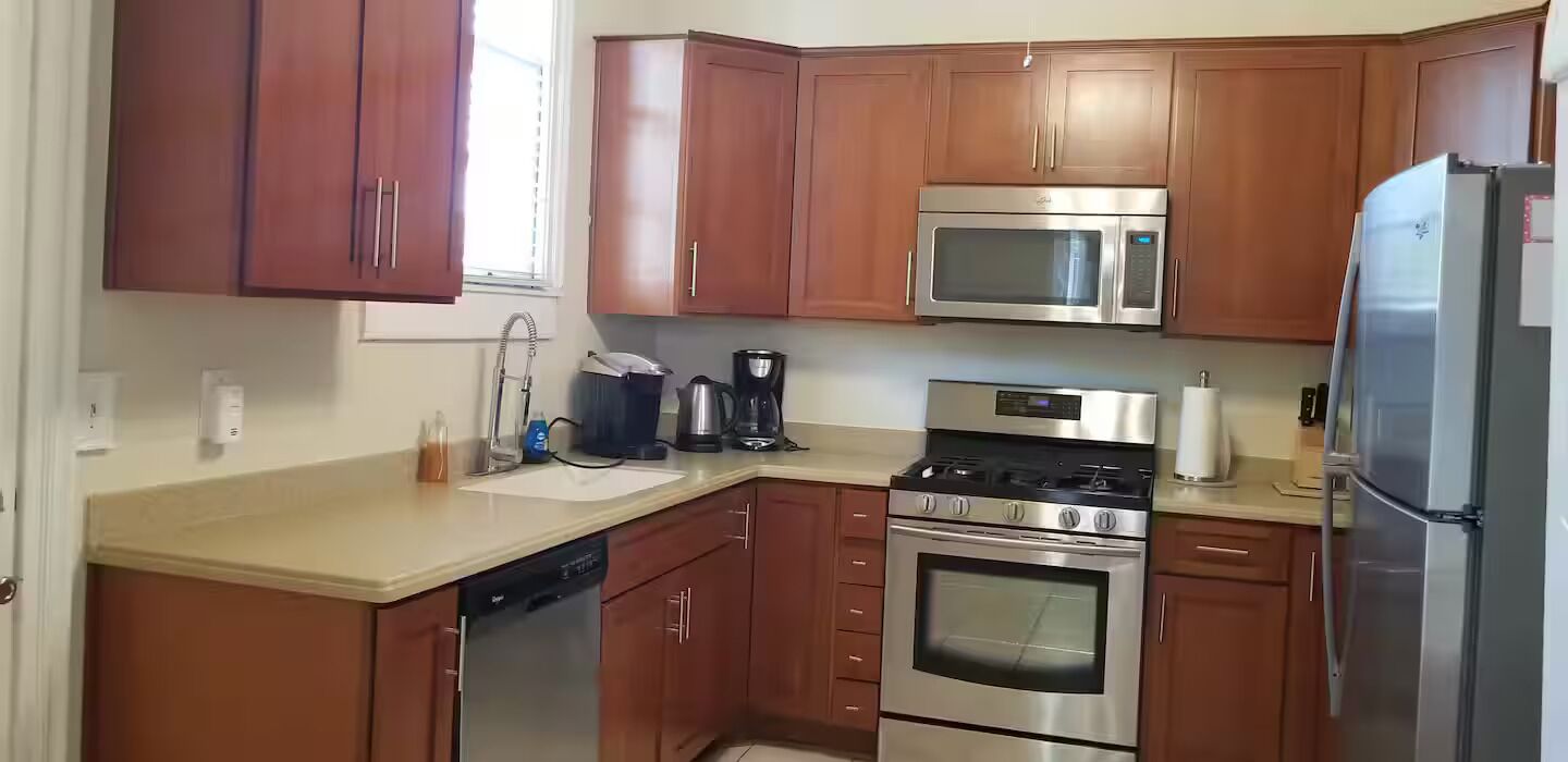 A kitchen with wooden cabinets, a stainless steel microwave, a refrigerator, a dishwasher, and a stove.