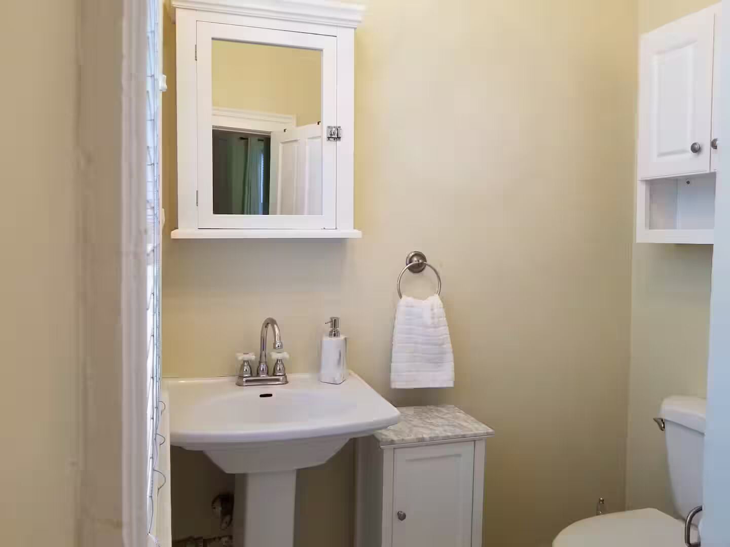 A bathroom with a white sink, a mirror above it, and a toilet.