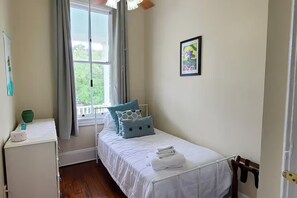 A bedroom with a single bed, a bedside table, a window with curtains, and a framed picture on the wall. - Apartment near Forsyth Park with free parking. 1.3 mile walk to River Street (Savannah)