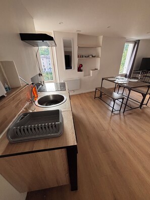 A modern kitchen with a built-in oven, a sink, and a dining area with a table and benches. - T2 downtown with parking and river view (Bédarieux)