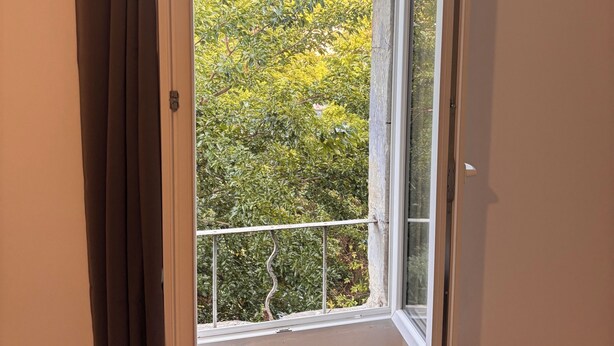 Una habitación con un ventanal grande, una cortina y suelo de madera.