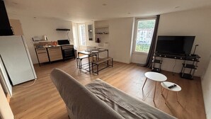 Un espacio habitable moderno con sofá, mesa de comedor, zona de cocina y televisión.