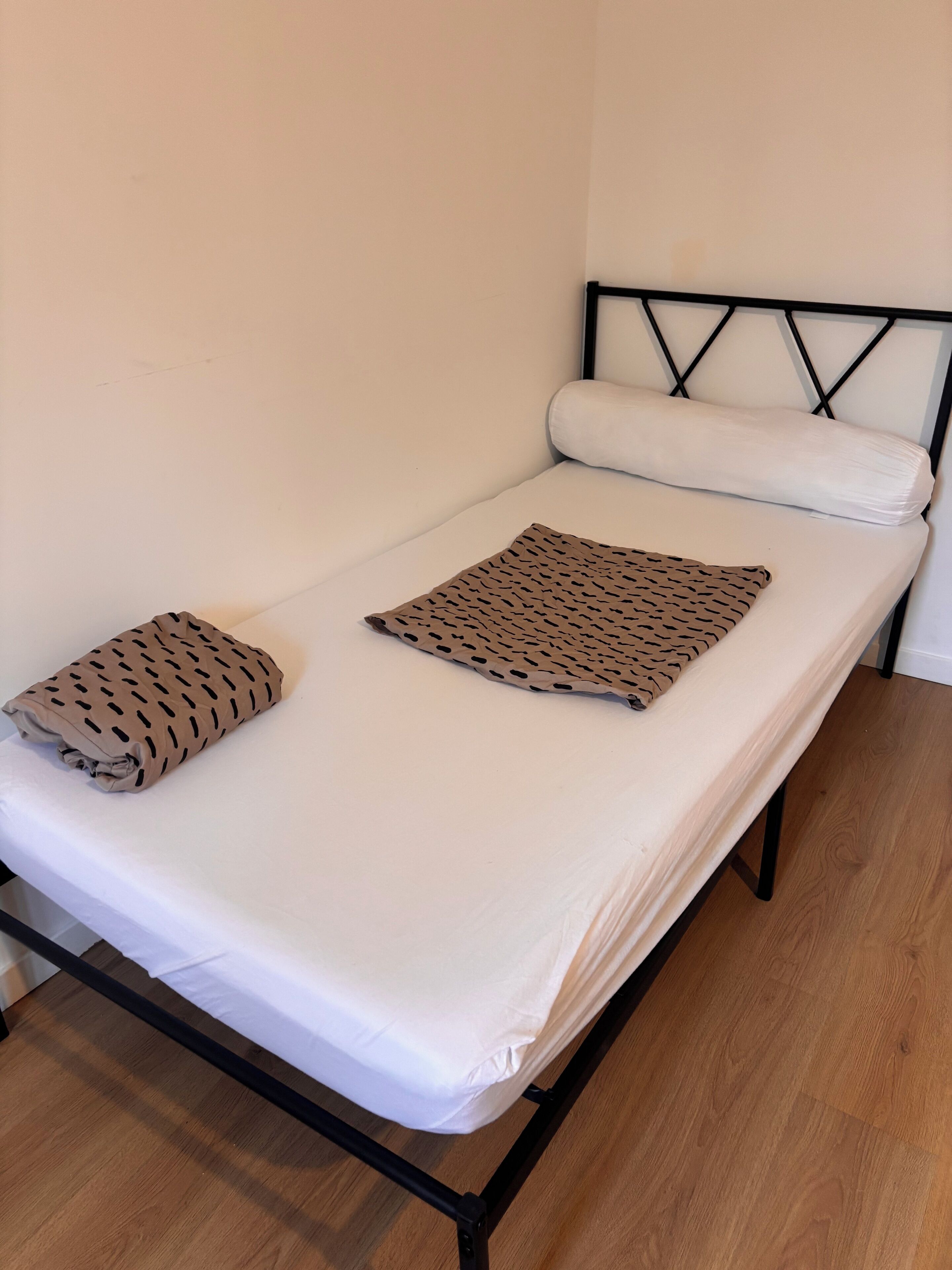 Un letto singolo con un materasso bianco e due cuscini, uno decorato con un motivo nero e l'altro liscio.