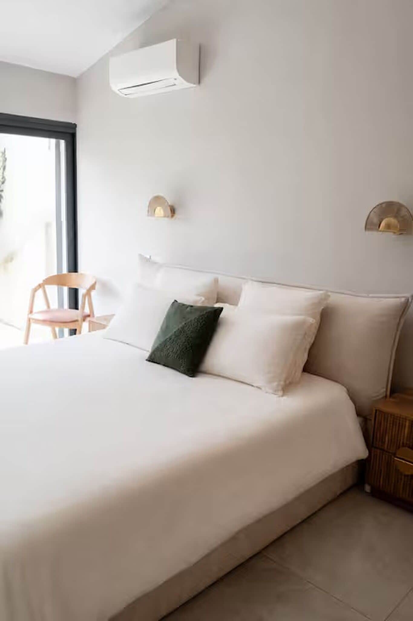 A modern bedroom with a large bed, a side table, and a chair.