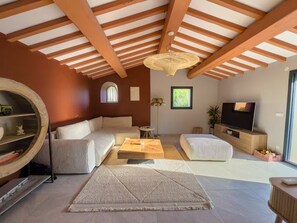 A modern living room with a sofa, a coffee table, a TV, and a large window. - Charming Villa with Pool – Grimaud / St-Tropez (Grimaud)