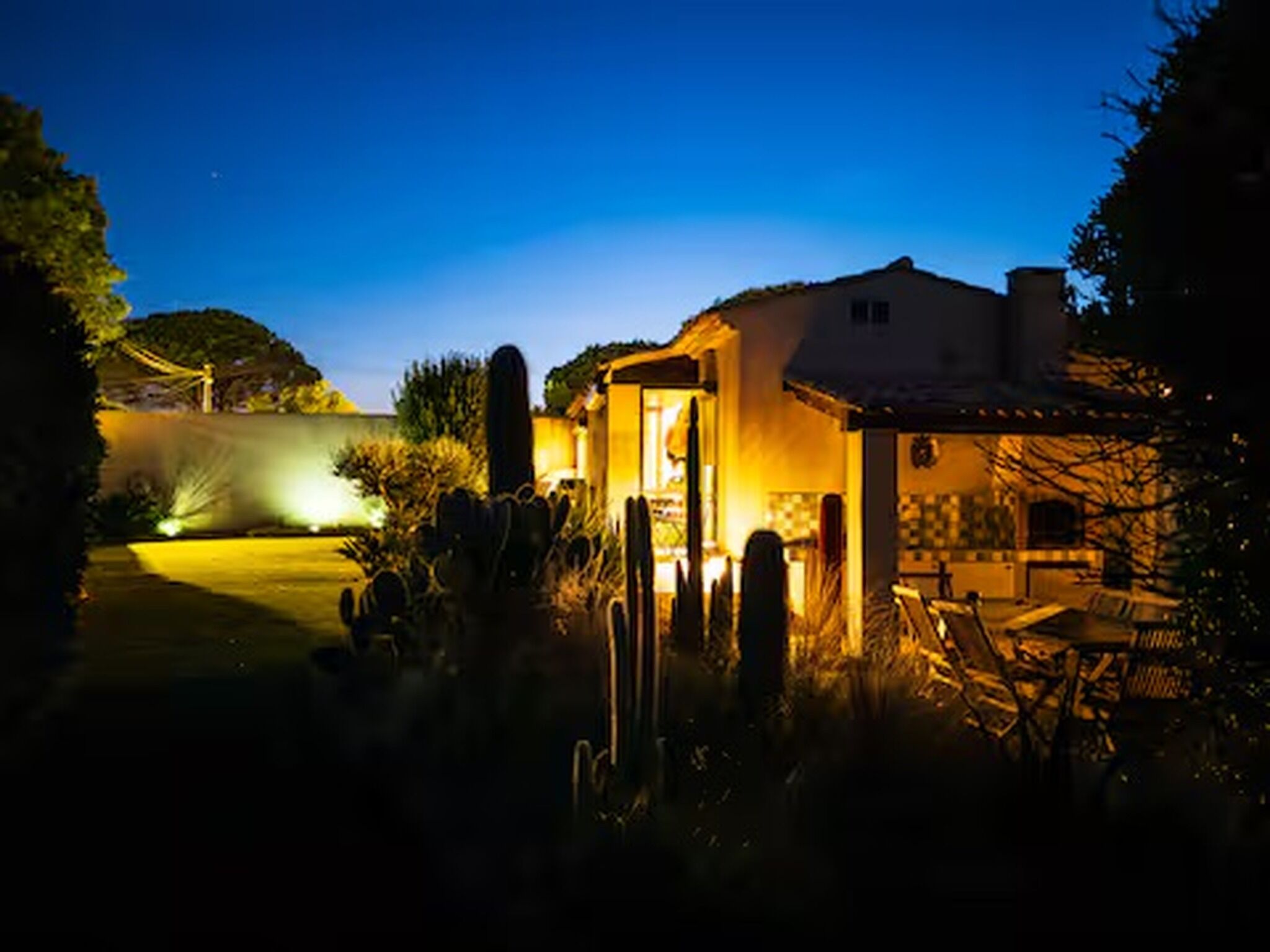 A residential property at dusk with a well-lit patio area and a visible garden.
