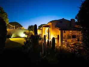 A residential property at dusk with a well-lit patio area and a visible garden. - Charming Villa with Pool – Grimaud / St-Tropez (Grimaud)