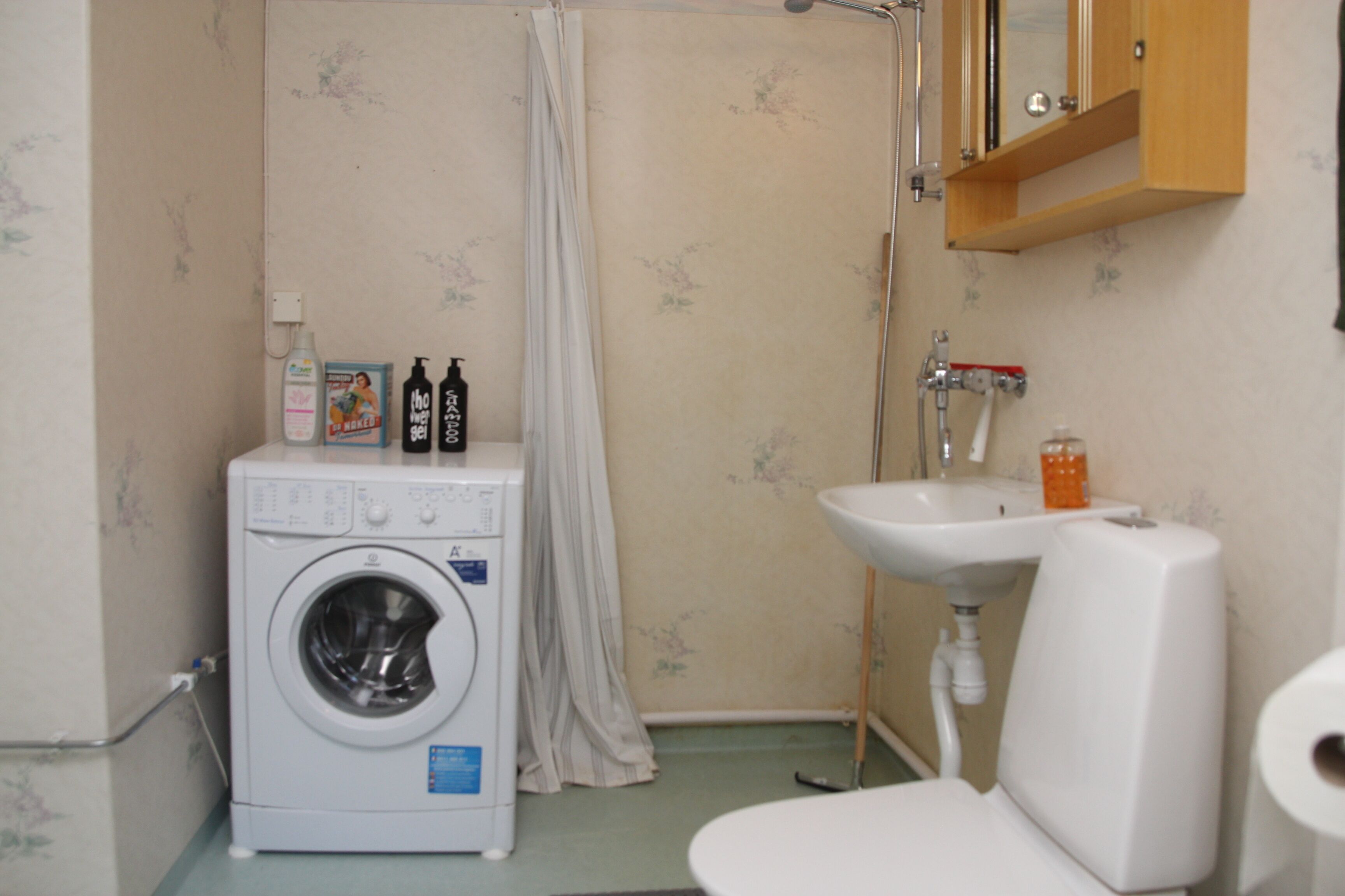 Un bagno compatto con lavatrice, lavandino e WC.