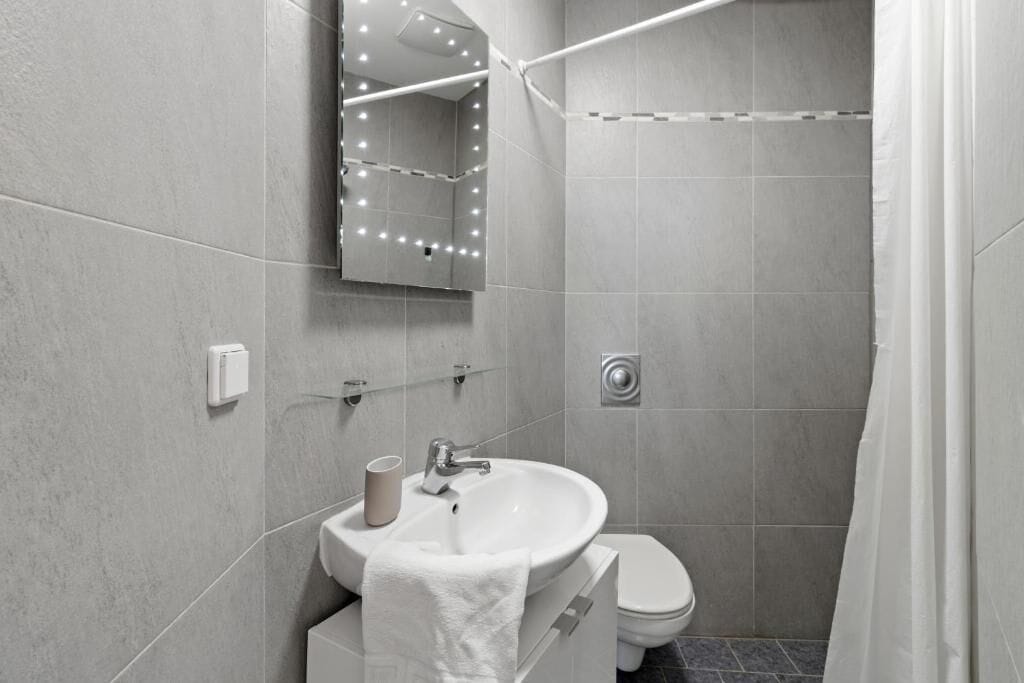 Un baño moderno con lavamanos, inodoro y zona de ducha.