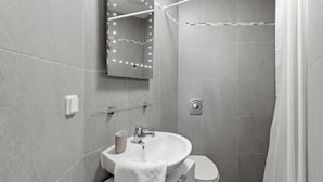 Un baño moderno con lavamanos, inodoro y zona de ducha.