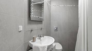 Un baño moderno con lavamanos, inodoro y zona de ducha.