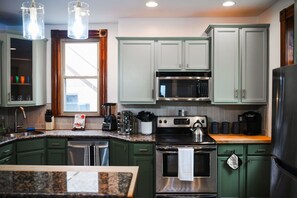 A kitchen with a stove, oven, microwave, and a window. - Sleeps 10 · Walk to Carson St · BBQ & Fire Pit (Pittsburgh)